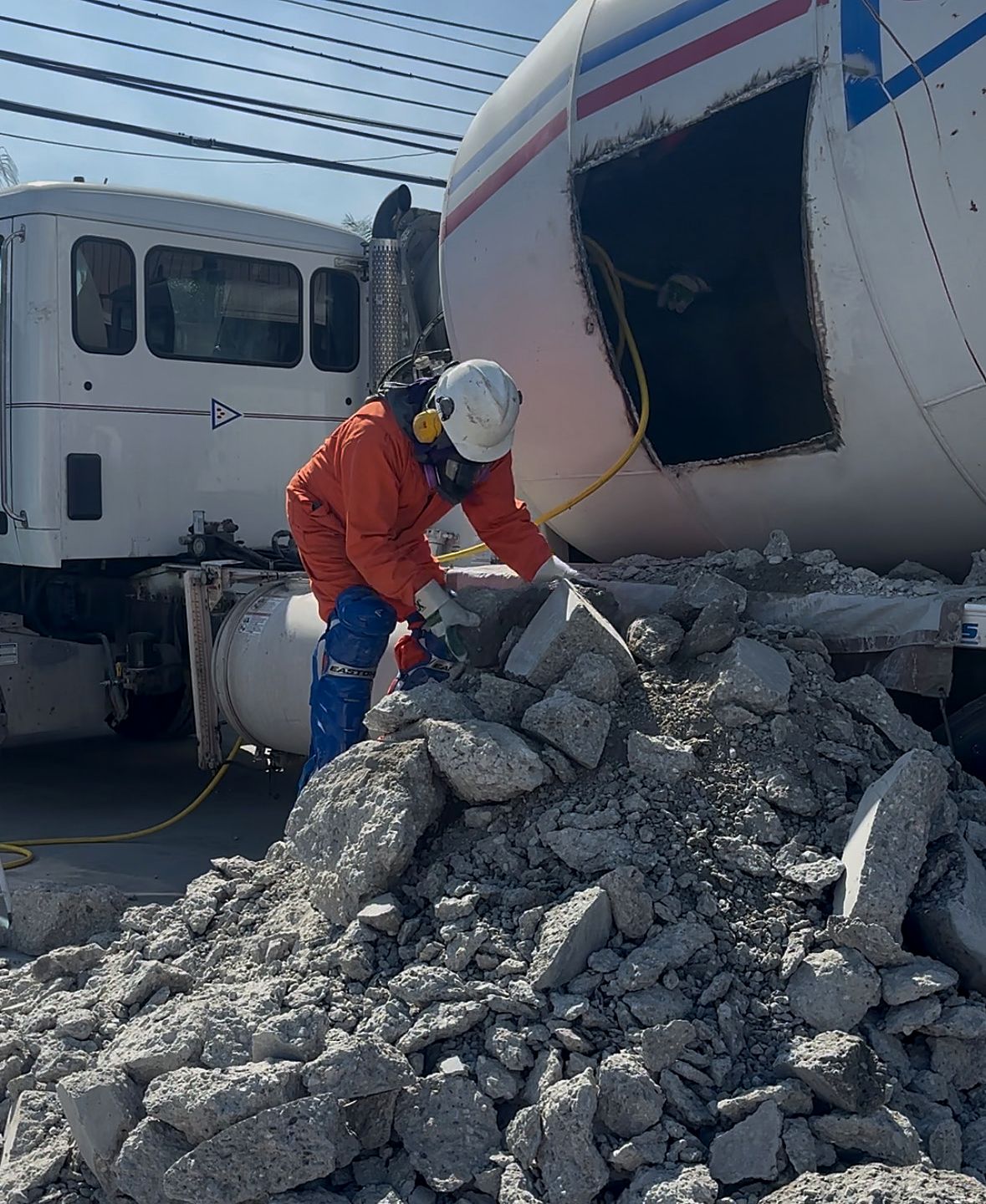 Express Chipping technician in full PPE breaking cured concrete removed from a ready mix drum at a customer plant